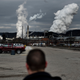 A man looks at smoke billowing from a coal-burning plant.